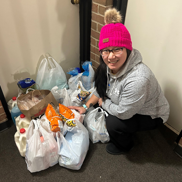 Johns Hopkins Medicine employee Lee Healy poses with groceries she delivers for Meals on Wheels of Central Maryland. 