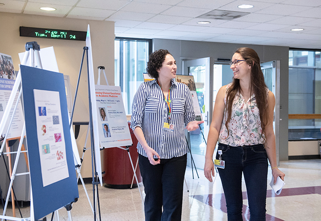 Two students walk down a hallway together, talking.