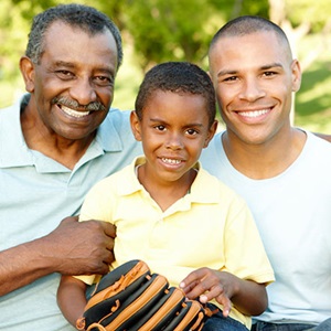 Child with a baseball glove sitting with his father and grandfather, smiling for the camera