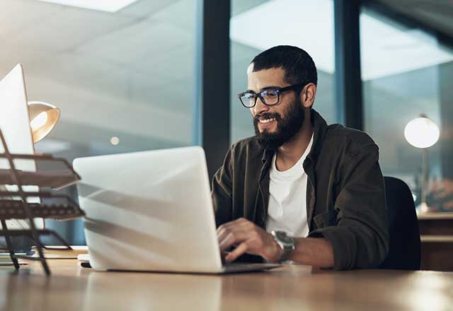 A smiling man in an office using his laptop