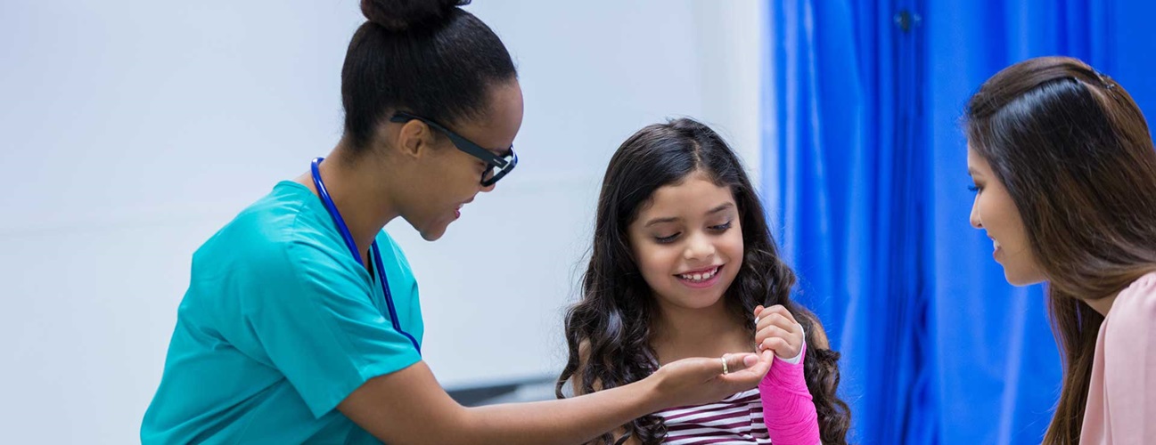 Doctor examines a young girl's wrist cast.