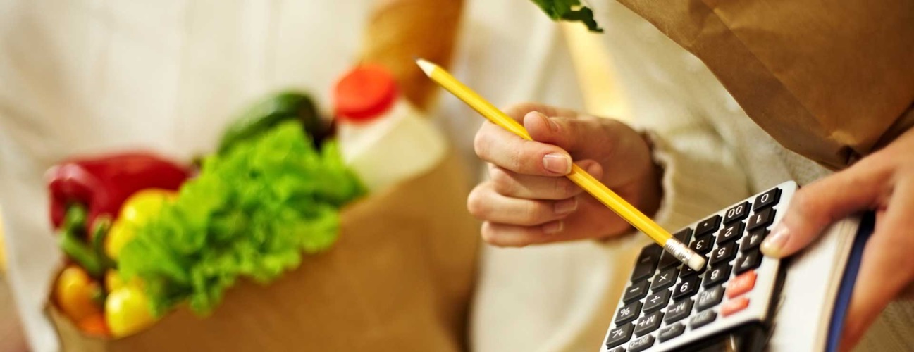 A woman with a calculator adding up groceries