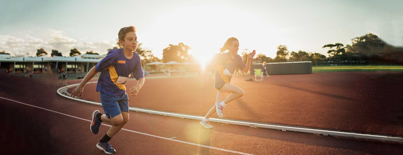 Two children running on a track field