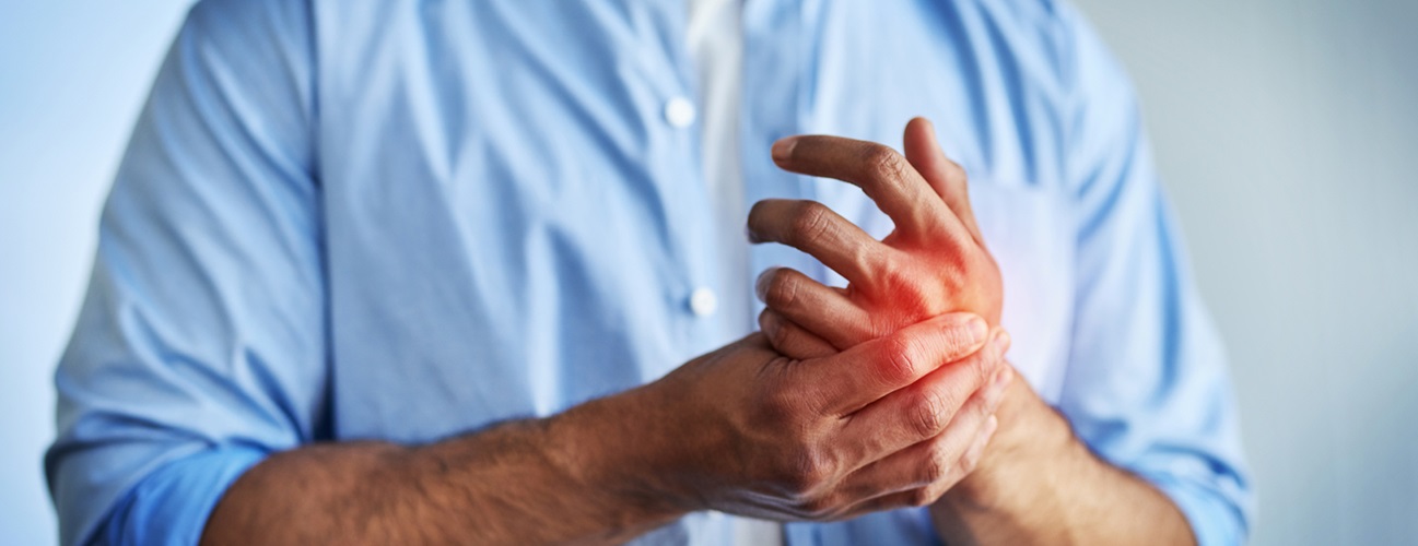 A man rubs his hand in pain.