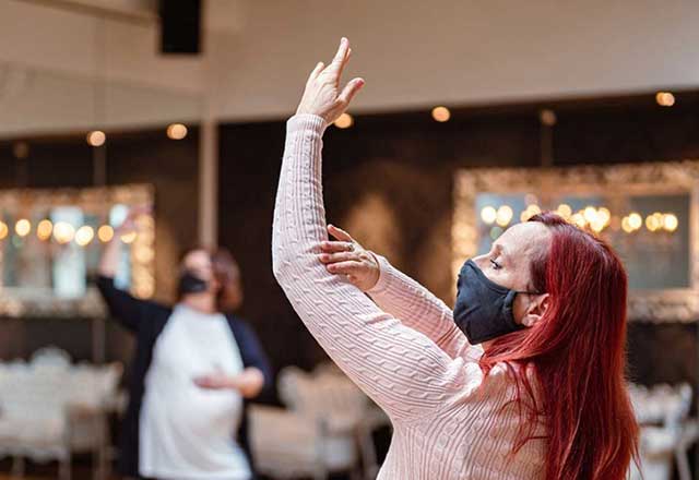 Performers practicing in a dance studio while wearing masks.