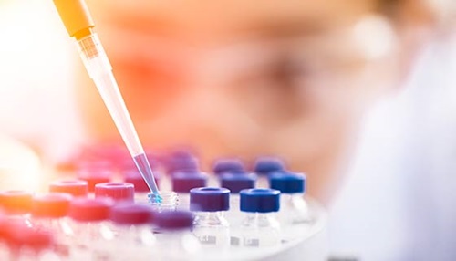 Scientist carefully insets a pipette into a test tube.