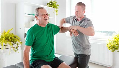 Physical therapist examining senior man's shoulder problem