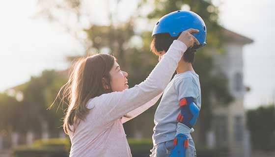 Mom strapping a biking helmet onto her child's head.