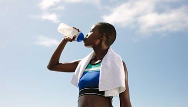 A woman after exercising drinking from a water bottle.