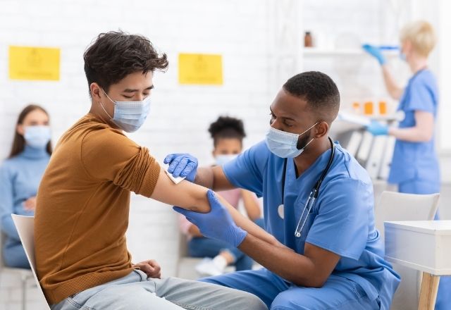 Masked young man receiving vaccine