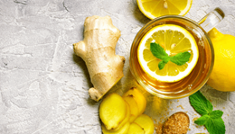 Ginger tea next to ginger power and ginger root on a table